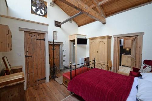 LothersdaleShed End, in 18th century Lothersdale Mill BD20 8EN的卧室配有红色的床和墙上的时钟