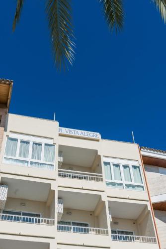 阿尔库迪亚港Hostal Vista Alegre的白色的建筑,上面有标志