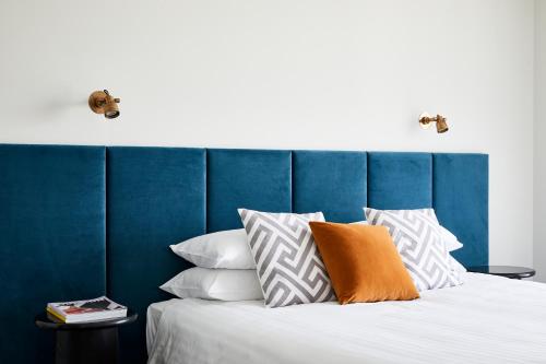 彭里斯Astina Suites, Penrith的一张带蓝色床头板和白色枕头的床