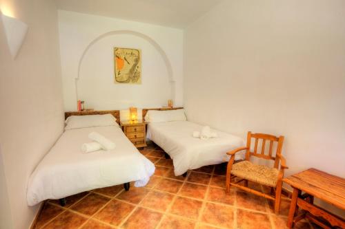圭哈尔谢拉Casa Rural Alba Montis的配有一张桌子和一把椅子的客房内的两张床