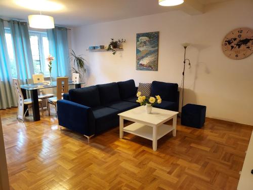 什切青APART- salon z aneksem kuchenym, 2 sypialnie, łazienka的客厅配有蓝色的沙发和桌子