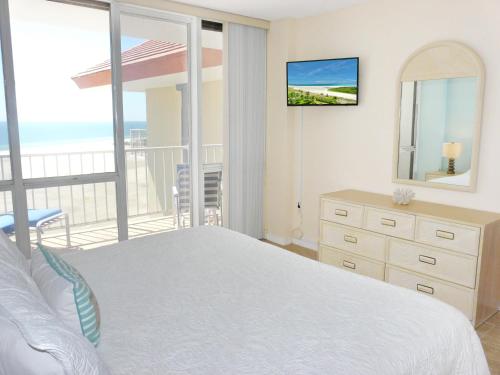 马可岛Tradewinds 1201的一间卧室设有一张床,阳台配有电视。