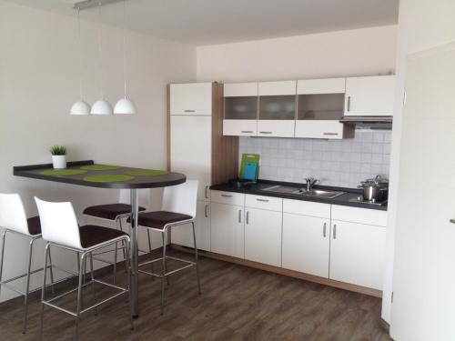 什未林Aparthotel am Heidensee的厨房配有白色橱柜和桌椅