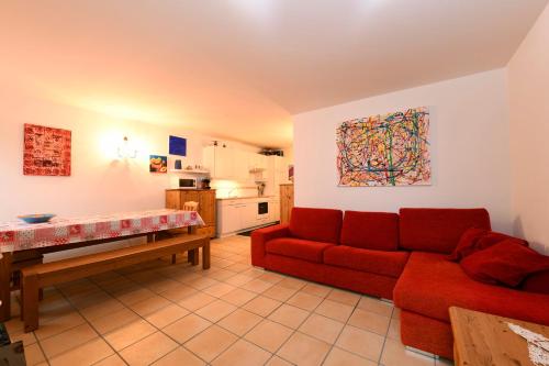 博斯克古林Bosco Gurin Nature & Ski的一间带红色沙发的客厅和一间厨房