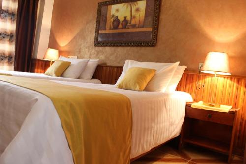 巴特纳Hotel el Hayat的酒店客房设有两张床,墙上挂着一张照片。