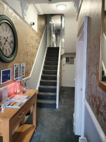 绍斯波特The Braemar Southport的走廊上设有楼梯,墙上有时钟