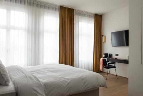 安特卫普Hotel Riga的一间卧室配有一张床和一张书桌及电视