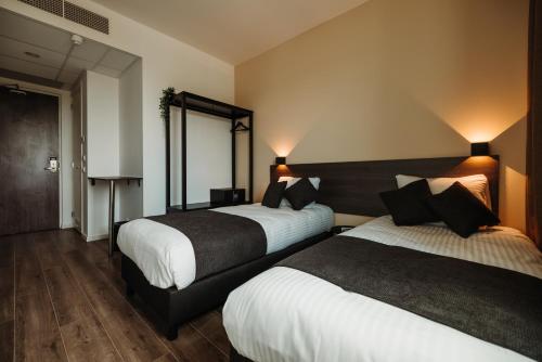 霍夫多普HOTELUX Amsterdam Airport Hotel的酒店客房,设有两张床和镜子