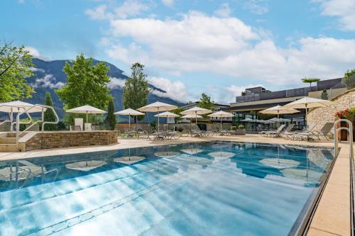 菲根黑尔德运动疗养四星级酒店的一个带椅子和遮阳伞的大型游泳池
