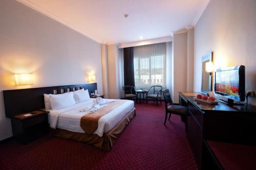 古邦Kristal Hotel Kupang的酒店客房配有一张床、一张书桌和一台电视。