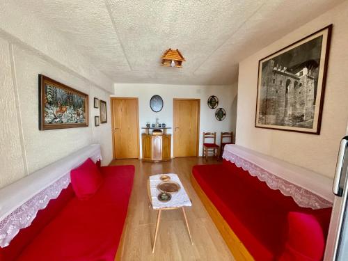 吉诺卡斯特Kubeja Guest House的客厅配有红色的沙发和桌子