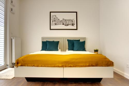 波兹南Essence Apartments Amber的一间卧室配有一张大床,提供黄色和蓝色的枕头