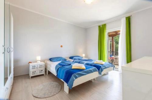耶塞尼采Kuca za odmor Veronika的一间卧室配有一张带蓝色床单和绿色窗帘的床