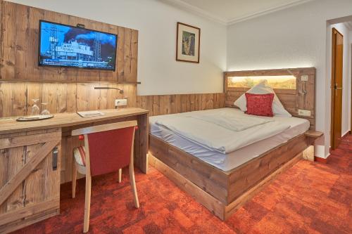 策勒伽尼酒店圣戈鲁格店的一间卧室配有一张床、一张书桌和一台电视