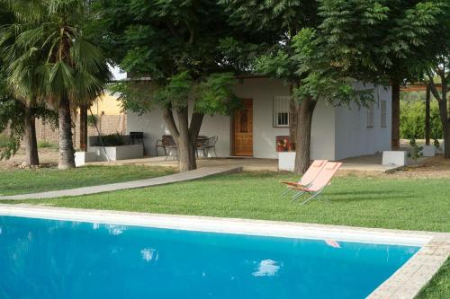 卡莫纳Preciosa y confortable casa de campo con piscina y chimenea的一座房子,旁边设有游泳池和椅子