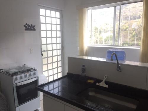 阿瓜斯迪林多亚Apartamento Turismo 2 quartos em Águas de Lindóia, Natureza!!!!的厨房配有水槽、炉灶和窗户。