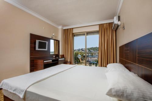 切什梅Suena hotel Çeşme的一间卧室配有一张床、一张书桌和一台电视