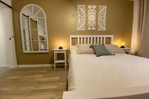 诺德什蒂Craftsman's House的一间卧室配有白色的床、两张桌子和镜子