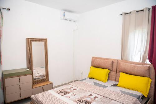 Mtsamgamoujiguest mtsangamouji F3的一间卧室配有一张带黄色枕头和镜子的床