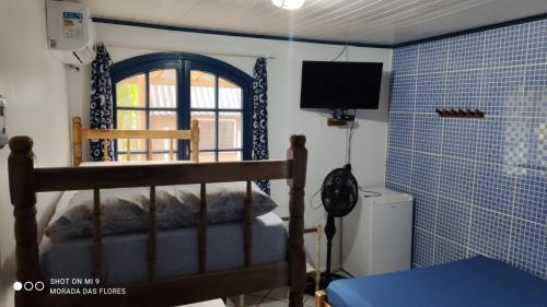 蜜岛Pousada Morada das Flores的一间卧室设有一张床、一个窗口和一台电视