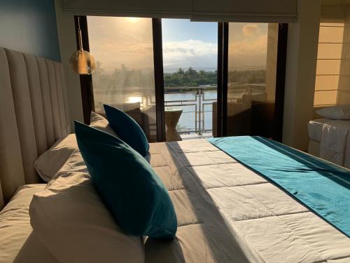 比亚米尔港Hotel La Laguna Galapagos的卧室配有带枕头的床铺和大窗户