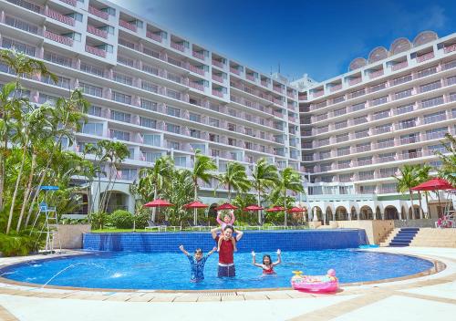 本部冲绳马海纳健康度假酒店的站在酒店前游泳池的家庭
