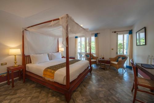 琅勃拉邦贝莱福精品酒店的一间卧室配有一张天蓬床和一张书桌