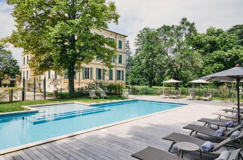 撒波兰Château de Montcaud的大楼前的带椅子和遮阳伞的游泳池