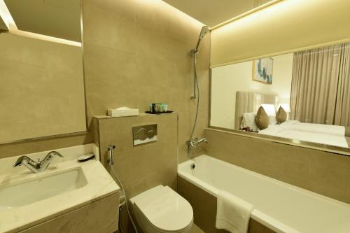 阿布扎比Saray Deluxe Hotel Apartments的一间带水槽、卫生间和镜子的浴室