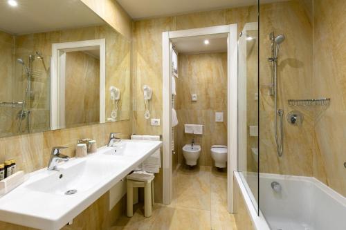 西尔米奥奈杜帕克酒店的一间带两个盥洗盆、淋浴和卫生间的浴室