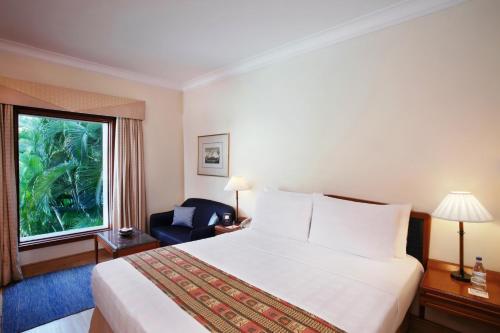 科钦特里丹特柯钦酒店的酒店的客房 - 带一张床、椅子和窗户