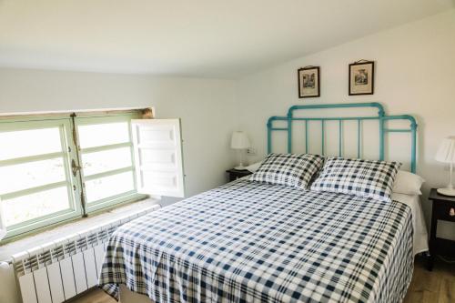 MeisSaramagoso的一间卧室配有一张带 ⁇ 子毯子的床和两个窗户