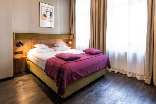 克拉科夫Liebeskind Boutique Hotel的酒店客房配有一张带紫色床单和枕头的床。