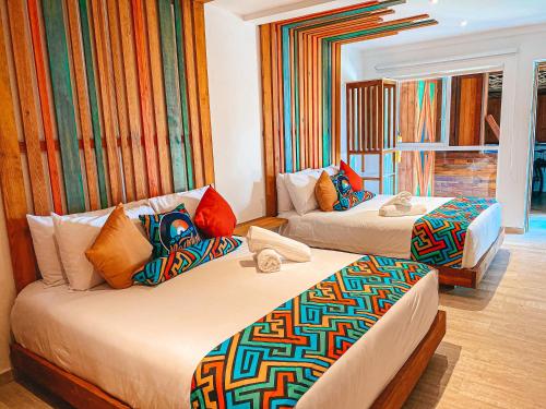 圣安德烈斯In Di House of Reggae Boutique的酒店客房配有两张带色彩缤纷枕头的床。