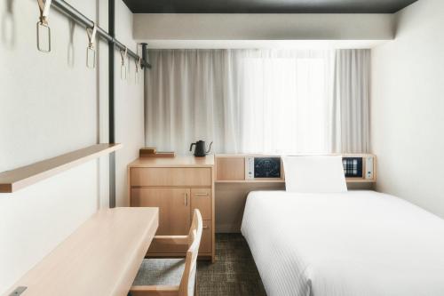 松山REF Matsuyama City Station by VESSEL HOTELS的一间卧室设有两张床、一张桌子和一个窗口。