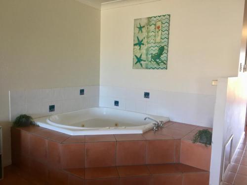 Elliott HeadsVilla 21 The Coral Cove Resort的带浴缸的浴室,铺有瓷砖地板
