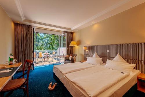 波茨坦波茨达姆酒店的酒店客房设有一张床、一张书桌和一个阳台。
