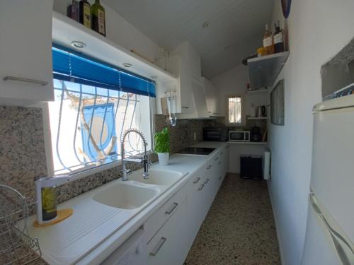 西让Maison de pecheur的白色的厨房设有水槽和窗户