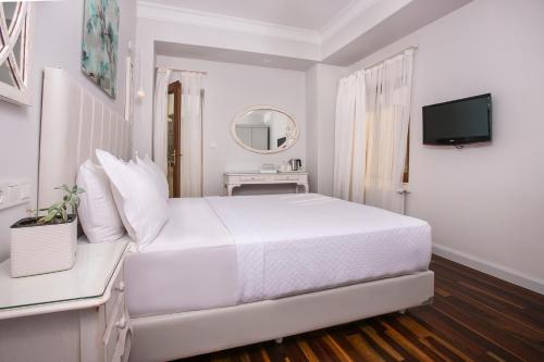 比于卡达Ascot Hotel Büyükada的白色的卧室配有白色的床和电视。