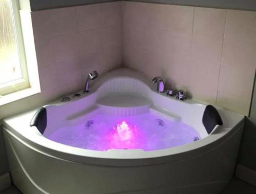 赫彻姆Inviting 2-Bed Bungalow in Heacham with spa bath的浴缸内有粉红色的灯光