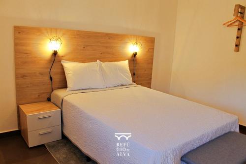 塞亚Refúgio do Alva - Serra da Estrela的卧室配有一张带两盏灯的墙壁床。