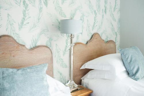 GaddesbyThe Cheney Arms的一间卧室配有一张带灯具和热带壁纸的床