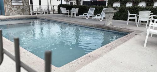 新拉雷多HOTEL LOS ROBLES的游泳池配有白色的桌椅