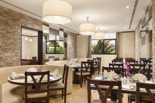 阿吉曼Ramada Hotel & Suites by Wyndham Ajman的用餐室设有桌椅和窗户。