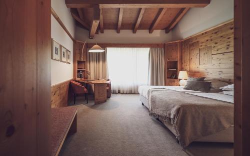 达沃斯Hotel Waldhuus的一间卧室配有一张床、一张书桌和一个窗户。