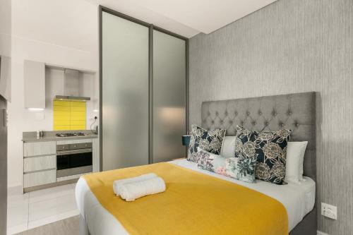 约翰内斯堡The Median Apartments的一间卧室配有一张带黄色毯子的大床