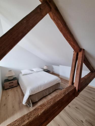 阿雷斯Le Crocolion的一间卧室配有一张铺有木地板的白色床单。