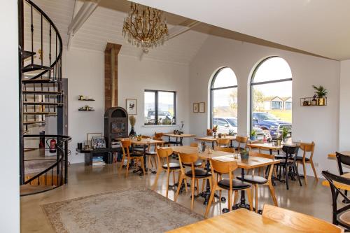 教堂城马格马酒店的餐厅设有木桌、椅子和窗户。