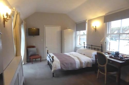 图克斯伯里科美尔顿皇冠酒店的一间卧室配有一张床、一张书桌和一张书桌