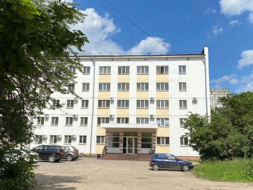 科纳科沃Konakovo Hotel的白色的建筑,有汽车停在停车场